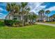 Beautiful home with lush green lawn, tropical palm trees and a brick paver driveway at 15033 Spanish Point Dr, Port Charlotte, FL 33981