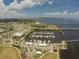 Aerial view of a marina and waterfront area with boats docked, palm trees, and buildings under a partly cloudy sky at 197 Colony Point Dr, Punta Gorda, FL 33950