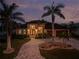 Elegant home featuring lush landscaping, stone driveway, and striking architecture under a twilight sky at 197 Colony Point Dr, Punta Gorda, FL 33950