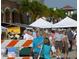 Street view of an outdoor market with tents, produce stands, and people browsing, indicating a vibrant community atmosphere at 197 Colony Point Dr, Punta Gorda, FL 33950