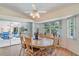 Dining area with wood floors, ceiling fan, and large windows overlooking the screened lanai and landscaping at 23488 Almond Ave, Port Charlotte, FL 33954