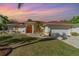 Exterior of home with manicured lawn, mature palms and bright orange front door at 23488 Almond Ave, Port Charlotte, FL 33954