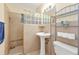 Bathroom with a pedestal sink, glass block window, and walk-in shower with tan colored tile at 2440 Ednor St, Port Charlotte, FL 33952