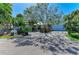 Well-manicured front yard with lush landscaping, mature trees, and a spacious driveway leading to the garage at 3790 Peace River Dr, Punta Gorda, FL 33983