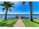 Waterfront property featuring a private dock extending into the serene water, framed by swaying palm trees and a well-manicured lawn at 3790 Peace River Dr, Punta Gorda, FL 33983