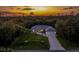Exterior home shot at dusk features landscaped front yard and concrete driveway with colorful sky backdrop at 4529 Enid Ln, North Port, FL 34288