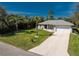 Well-maintained home featuring a large, green front lawn, palm trees, and a concrete driveway leading to a two-car garage at 4529 Enid Ln, North Port, FL 34288