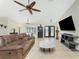 Living room featuring tiled floors, a ceiling fan, a sofa, a bookshelf, a TV, and lots of natural light at 4529 Enid Ln, North Port, FL 34288