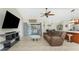 Open-concept living room with tiled flooring, a ceiling fan, a sofa, a kitchen bar, and a view of the screened-in patio at 4529 Enid Ln, North Port, FL 34288