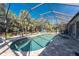 Sparkling screened-in pool with brick paver deck and surrounding tropical landscaping, perfect for relaxation at 4529 Enid Ln, North Port, FL 34288