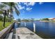 Dock overlooking beautiful blue waterway with boats, palm trees, and serene skies at 494 Monaco Dr, Punta Gorda, FL 33950