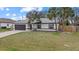 Charming single-story home with a well-manicured lawn, palm trees, and a two-car garage at 5113 Weatherton St, North Port, FL 34288