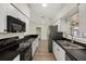 Galley kitchen featuring stainless steel appliances, wood-look flooring and black countertops at 5113 Weatherton St, North Port, FL 34288