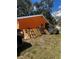 Backyard view of an orange home, various yard items stored against house at 5240 Malamin Rd, North Port, FL 34287