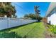 Spacious backyard with lush lawn, white picket fence, and tropical landscaping at 621 Trabue Ave, Punta Gorda, FL 33950