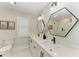 Bright bathroom with double vanity, geometric mirrors, white cabinets, and modern fixtures at 621 Trabue Ave, Punta Gorda, FL 33950