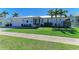 Charming single-story home featuring well-manicured landscaping, lush lawn, and a white metal roof in a sunny, tropical setting at 621 Trabue Ave, Punta Gorda, FL 33950
