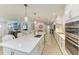 A modern kitchen island featuring pendant lighting, white cabinets, and stainless steel appliances with an open floor plan at 621 Trabue Ave, Punta Gorda, FL 33950