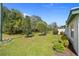 Spacious backyard featuring a well-manicured lawn, mature trees, lush green shrubbery and landscaping at 726 Connemara Ct, Venice, FL 34292