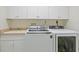 Bright laundry room featuring a washer, dryer, sink, and ample upper and lower cabinet storage at 726 Connemara Ct, Venice, FL 34292