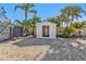 Backyard shed featuring an open door, gravel ground cover, surrounded by tropical landscaping and a privacy fence at 20343 Rutherford Ave, Port Charlotte, FL 33952