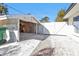 Open carport with a white privacy fence and sidewalk access, featuring decorative rock cover at 20343 Rutherford Ave, Port Charlotte, FL 33952