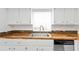 Bright kitchen with white cabinets, stainless steel sink, wood counters and stainless steel dishwasher at 20343 Rutherford Ave, Port Charlotte, FL 33952