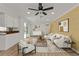 A bright, staged living room features wood-look floors, ceiling fan, neutral walls, and stylish furniture at 20343 Rutherford Ave, Port Charlotte, FL 33952