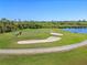Scenic golf course view with sand traps and a tranquil water feature in a lush, green setting under a clear blue sky at 1321 Eagles Flight Way, North Port, FL 34287