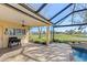 Spacious lanai with brick pavers, ceiling fan, a built-in grill, and a pool with tranquil backyard views at 1321 Eagles Flight Way, North Port, FL 34287