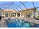 An expansive screened lanai showcasing a shimmering pool, a spa, and an outdoor dining area at 1321 Eagles Flight Way, North Port, FL 34287