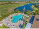 An inviting community pool featuring ample lounge seating, palm trees, and a serene lake with a fountain at 1321 Eagles Flight Way, North Port, FL 34287