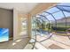 An inviting screened pool and hot tub with lush landscaping seen through sliding glass doors at 1321 Eagles Flight Way, North Port, FL 34287