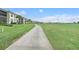 Scenic walkway along greens, with condos in the background under a bright blue sky at 15970 Grassland Ln # 2816, Punta Gorda, FL 33982