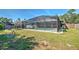 Exterior view of screened pool in private backyard featuring lush, green grass and a white vinyl fence at 21229 Giddings Ave, Port Charlotte, FL 33952