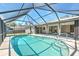 A private in-ground screened pool featuring a sun shelf, blue tile trim, and access to the porch at 21229 Giddings Ave, Port Charlotte, FL 33952