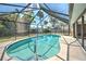 Screened in-ground pool surrounded by lush backyard landscaping offering privacy at 21229 Giddings Ave, Port Charlotte, FL 33952