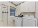 Bright laundry room with a washer, dryer, storage cabinets, and a window for natural light at 2181 Via Seville, Punta Gorda, FL 33950
