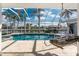 Inviting screened-in pool with a hanging chair, canal view, and tropical landscaping at 2181 Via Seville, Punta Gorda, FL 33950