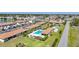 Aerial view of a community with a swimming pool, bocce ball court, and mature landscaping near a lake at 25275 Rampart Blvd # 1602, Punta Gorda, FL 33983