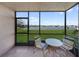 Enclosed lanai features a table and chairs overlooking a lush green lawn and lake view at 25275 Rampart Blvd # 1602, Punta Gorda, FL 33983