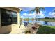 Backyard patio offers seating area overlooking pond, palm tree, and lush landscaping at 26034 Feathersound Dr, Punta Gorda, FL 33955