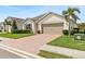 Charming single-story home with a well-manicured lawn, brick paver driveway, palm tree, and two car garage at 3860 Cobblestone Ln, Punta Gorda, FL 33980