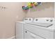 Functional laundry area with modern white washer and dryer units and storage shelving at 3860 Cobblestone Ln, Punta Gorda, FL 33980
