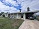 Quaint single-story home with covered parking and landscaped front yard under cloudy sky at 4045 Conway Blvd, Port Charlotte, FL 33952