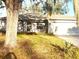 Home exterior with a lawn in need of maintenance and mature shade tree at 5098 Adina Cir, North Port, FL 34291