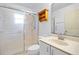 Bright bathroom featuring a glass-enclosed shower, single sink vanity, and decorative wooden wall shelving at 5215 Ariton Rd, North Port, FL 34288