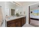 Bathroom with double sinks, a large mirror, and a doorway leading to a bedroom at 7304 W Lenox Circle, Punta Gorda, FL 33950