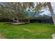 Spacious backyard featuring a mature shade tree, lush landscaping, and screened porch at 75 Spyglass Aly, Placida, FL 33946