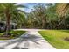 Green lawn with a circular driveway lined with mature trees leading to the home at 75 Spyglass Aly, Placida, FL 33946